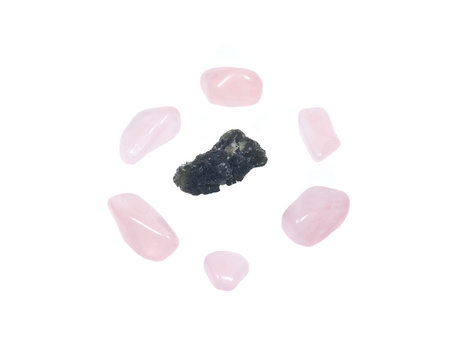 Moldavite - form of tektite found along the banks of the river Moldau in Czech republic, isolated on white background, surrounded by tumbled rose quartz pieces 