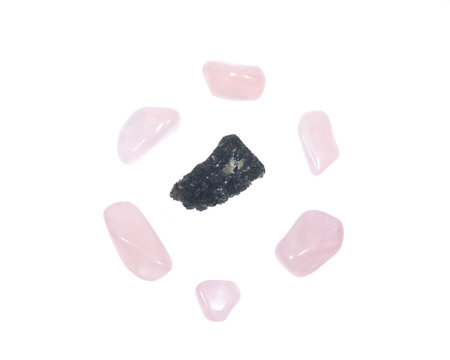 Moldavite - form of tektite found along the banks of the river Moldau in Czech republic, isolated on white background, surrounded by tumbled rose quartz pieces 