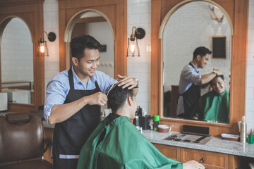 man getting haircut by hairdresser at barbershop