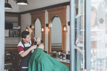 man getting haircut by hairdresser at barbershop