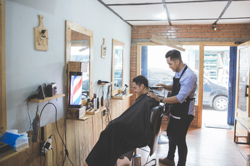 man getting haircut by hairdresser at barbershop