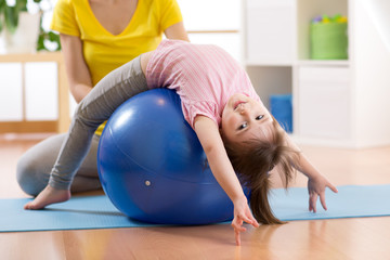 Cute child girl stretching on pilates fitness ball in gym