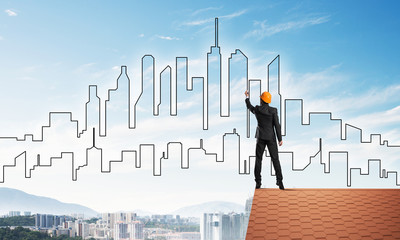 Man architect draw silhouette of modern city on blue sky. Mixed media
