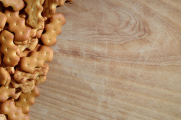 A lot of salt cracker lies on an old wooden cutting board with cuts and scars. Photo of a golden...