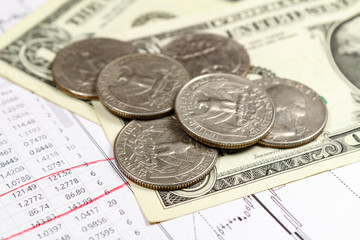 US dollars banknotes with coins on the background of currency growth schedule. Focus in the foreground