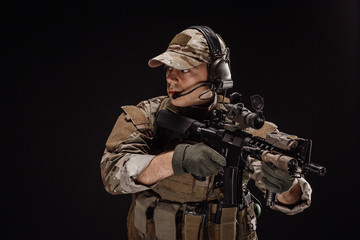 Fototapeta premium Portrait soldier or private military contractor holding sniper rifle. war, army, weapon, technology and people concept. Image on a black background.
