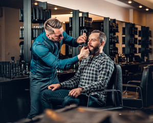 Stylish barber grooming a man's beard in a saloon.