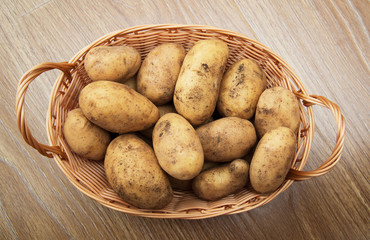 Plakat Raw potatoes in a basket on a wooden table