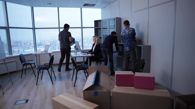 The Work is Not Waiting/The team of young designers is moving into new office. The boss is already working, taking care of clients