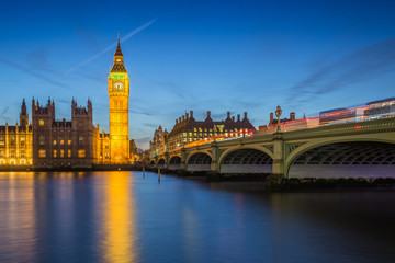 Fototapeta premium London, England - The Big Ben Clock Tower and Houses of Parliament with iconic red double-decker buses at city of westminster by night