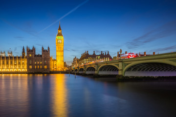 Fototapeta premium London, England - The Big Ben Clock Tower and Houses of Parliament with iconic red double-decker buses at city of westminster by night
