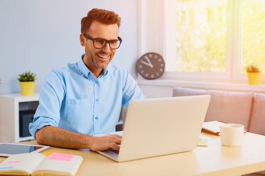 Happy man working with laptop from home