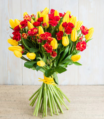 Bouquet of tulips and bush roses on a wooden background