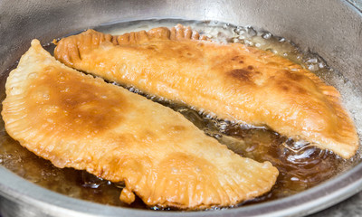 Patties with meat frying in oil in frying pan.