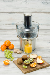 Modern electric juicer, various fruit and glass of freshly made juice, healthy lifestyle concept