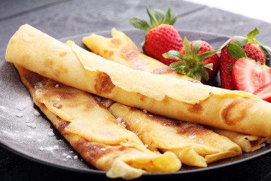Crepes with jam, strawberries and sugar powder. Homemade pancakes, delicious breakfast