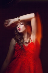 Blurred color art portrait of a girl on a dark background. Fashion woman with beautiful makeup and a light summer dress. Sensual tender image of a girl in motion. Studio portrait