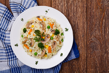 Classic Risotto with mushrooms and vegetables served on a white plate.