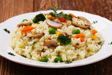 Classic Risotto with mushrooms and vegetables served on a white plate.