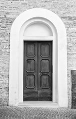 Wooden door in an old Italian house, copy-space, black and white.