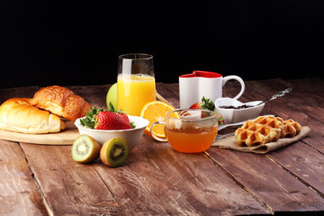 breakfast on table with waffles, croissants, coffe and juice