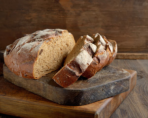 Black homemade bread sliced on a wooden background