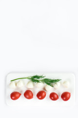 Top view of a fresh contrasting picture of a duet of small tomatoes and expensive cheese isolated in white, copy space. Healthy foods, cooking and vegetarian concept summer vegetables border.