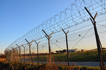 Fence with barbed wire on the sky background.