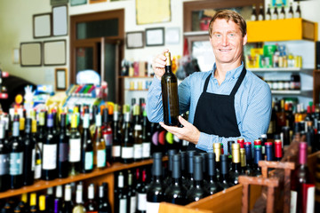 Male seller with wine bottle in hands