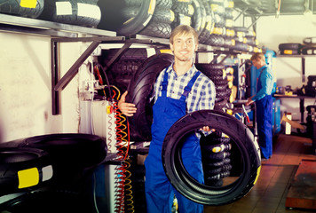 Obraz na płótnie Canvas Happy working man standing with new tires