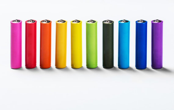 Different colors of alkaline batteries on a light background