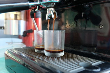 Porta filter espressomachine flow hot coffee to glass, Barista hand using a tamper to press ground coffee into a portafilter
