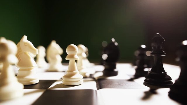 Still shot of the white and black pieces on a chess board, with shallow depth of field and focus transition.
