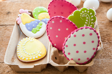 Close up of variety of colorful ester egg cookies with icing decoration in a craft paper container...