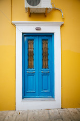 Dark blue old door with glass and forging on a yellow-and-white wall