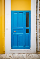 Dark blue old door with glass and forging on a yellow-and-white wall