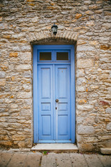 Fototapeta na wymiar Light blue old door on a stone wall