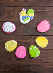 Close up of variety of colorful ester egg cookies with icing decoration in a craft paper container on a wooden background.