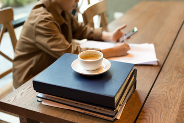 Selected focus coffee cup on top of folders with student writing paper
