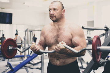 The adult brutal man is engaged in power bodybuilding in the gym 