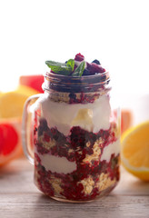 Breakfast cereal and citrus.Muesli, fresh berries and yogurt in glass mason jar on wooden table. Healthy breakfast with Homemade granola