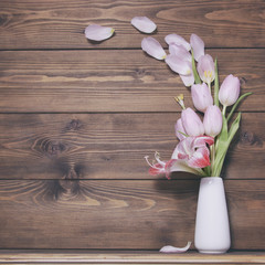 Wooden background witn pink tulip flowers and amaryllis on vese