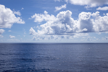 Blue sky, clouds and tranquil water at sea with horizon