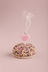 birthday cake with heart shaped candle on pink