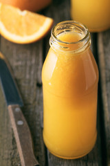 Close-up of bottle of fresh orange juice on rustic wooden table