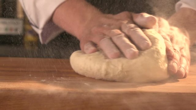 Baker prepares bread. man's hands working the dough on table covered with flour. Slowmotion. Close-up