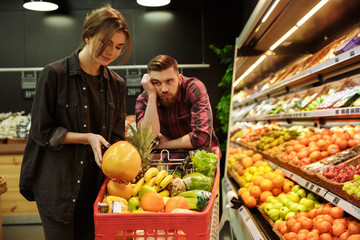 Loving couple in supermarket with shopping trolley