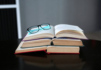 Open stack hardback books with glasses on wooden table. Education background.