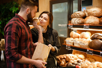 Cheerful loving couple in supermarket smells and choosing pastries.