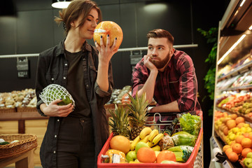 Fototapeta premium Loving couple in supermarket with shopping trolley